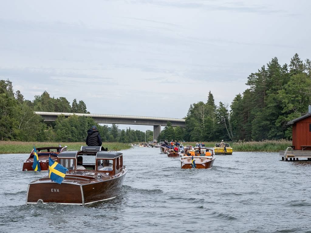 Konvoj av klassiska träbåtar i ett sund